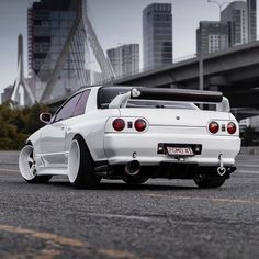 the back end of a white car parked in front of a bridge