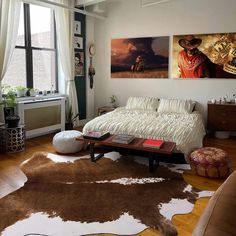 a living room filled with furniture and paintings on the wall next to a wooden floor