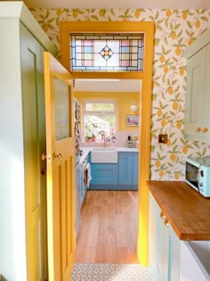 an open door leading to a kitchen with blue cabinets and yellow accents on the walls