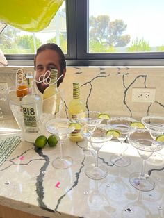 a man sitting at a table with wine glasses and bottles in front of his face