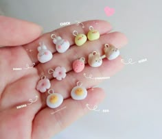 a person's hand holding several tiny toy animals and eggs in different colors, sizes and shapes