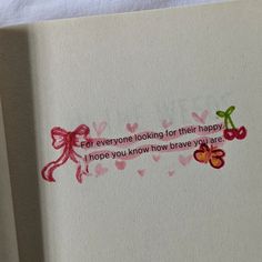 an open book with some writing on the cover and two cherries in pinks