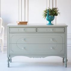 a blue vase sitting on top of a white dresser