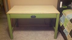 a small green table sitting next to a bed