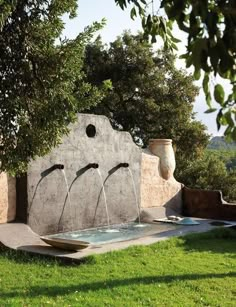 an outdoor fountain with water running from it's sides and two vases on each side