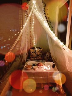 a bed that has some food on it in front of a window with lights around it