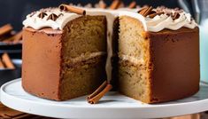 a cake that has been cut in half on a plate with cinnamon sticks around it