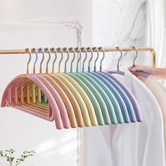 a person is holding a rack with several colored hangers in front of a white wall