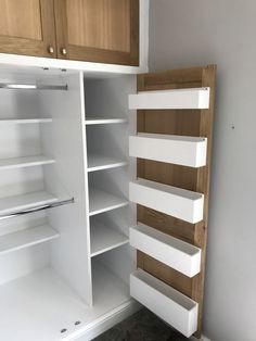 an empty pantry with white shelves and wooden cupboards on both sides, in the corner of a room