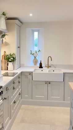 a white kitchen with lots of counter space and plants on the window sill above the sink