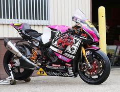 a pink and black motorcycle parked in front of a building