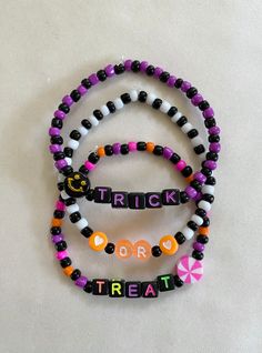 three bracelets that say trick or treat and one has candy on it with the word trick written in small letters