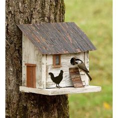 two birds sitting on top of a birdhouse next to a tree in the grass