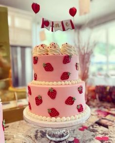 a pink cake with strawberries on it sitting on a table next to other desserts