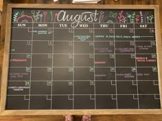 a chalkboard with a calendar on it in front of a person's feet