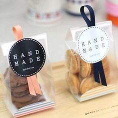 two bags of cookies sitting on top of a wooden cutting board with ribbons around them