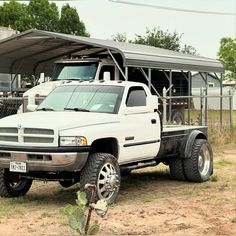 a white truck parked in front of a metal structure with a canopy over it's roof