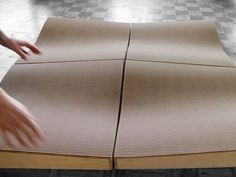 a person reaching for something on top of a piece of cardboard that is laying on the floor