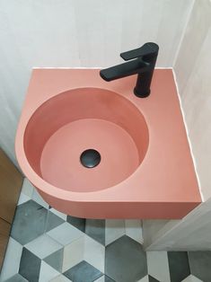 a pink sink with black faucet in a bathroom