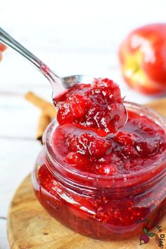 a spoon full of cranberry sauce sitting on top of a wooden cutting board