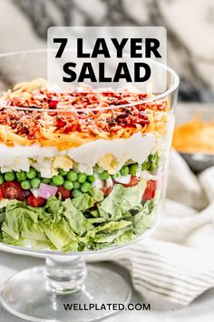 a layered salad in a glass dish with the words 7 layer salad on top and below it