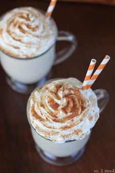 two cups filled with whipped cream and orange striped straws