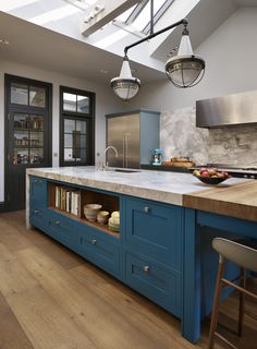 a kitchen with blue cabinets and an island in the middle is lit by two pendant lights