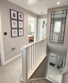 a staircase with pictures on the wall and mirror above it, leading to another room