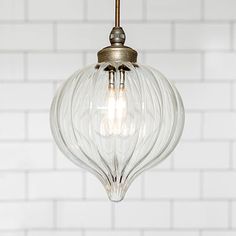 a clear glass light fixture hanging from a white brick wall in a kitchen or dining room