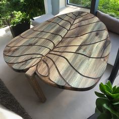 a wooden table sitting on top of a white floor next to a plant and window