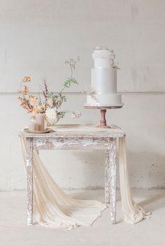 a white cake sitting on top of a table next to vases filled with flowers