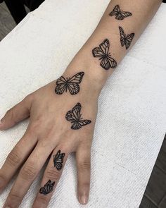 a woman's hand with black butterflies on the left side of her right arm