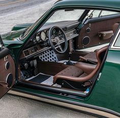 the interior of a green car with brown leather seats and steering wheel hubs is shown