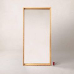 an empty wooden frame with a red object on the floor in front of it and a white background