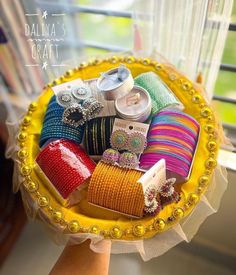 a yellow basket filled with lots of different types of bracelets and other jewelry on top of a window sill