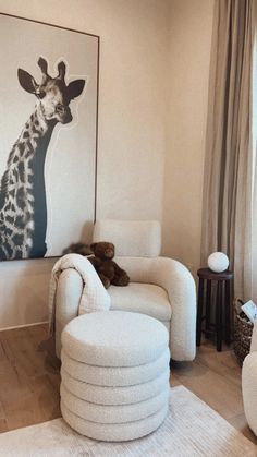 a living room filled with white furniture and a giraffe painting on the wall