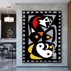 an abstract painting in black, yellow and red on a wall next to a dining room table