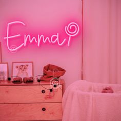 a pink neon sign above a dresser in a room with a baby's crib