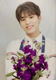 a young man holding a bouquet of purple flowers