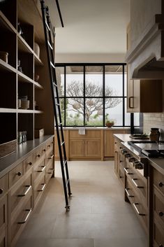 a ladder is in the middle of a large kitchen with wooden cabinets and open shelves