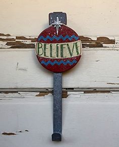 a metal hook with the word believe painted on it