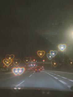 cars driving down the road with heart shaped lights on it's windshield at night