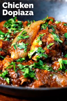 chicken doppiaza with parsley on top in a black bowl over a wooden table