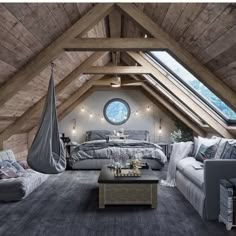 an attic bedroom is decorated in gray and white with lots of natural wood beams, exposed lighting, and a hammock hanging from the ceiling