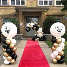 an entrance decorated with black, white and gold balloons