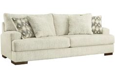 a white couch with pillows on it and two throw pillows sitting on the armrests