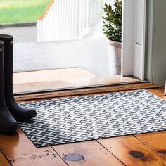 a pair of black boots sitting on top of a door mat