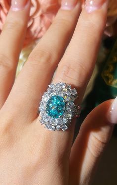 a close up of a person's hand with a ring on their finger and a flower in the background