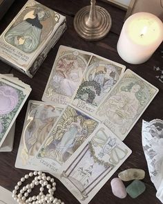 some cards are laying out on a table next to a candle and other items that have been placed around them