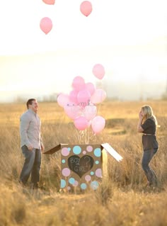 two people standing in a field with balloons